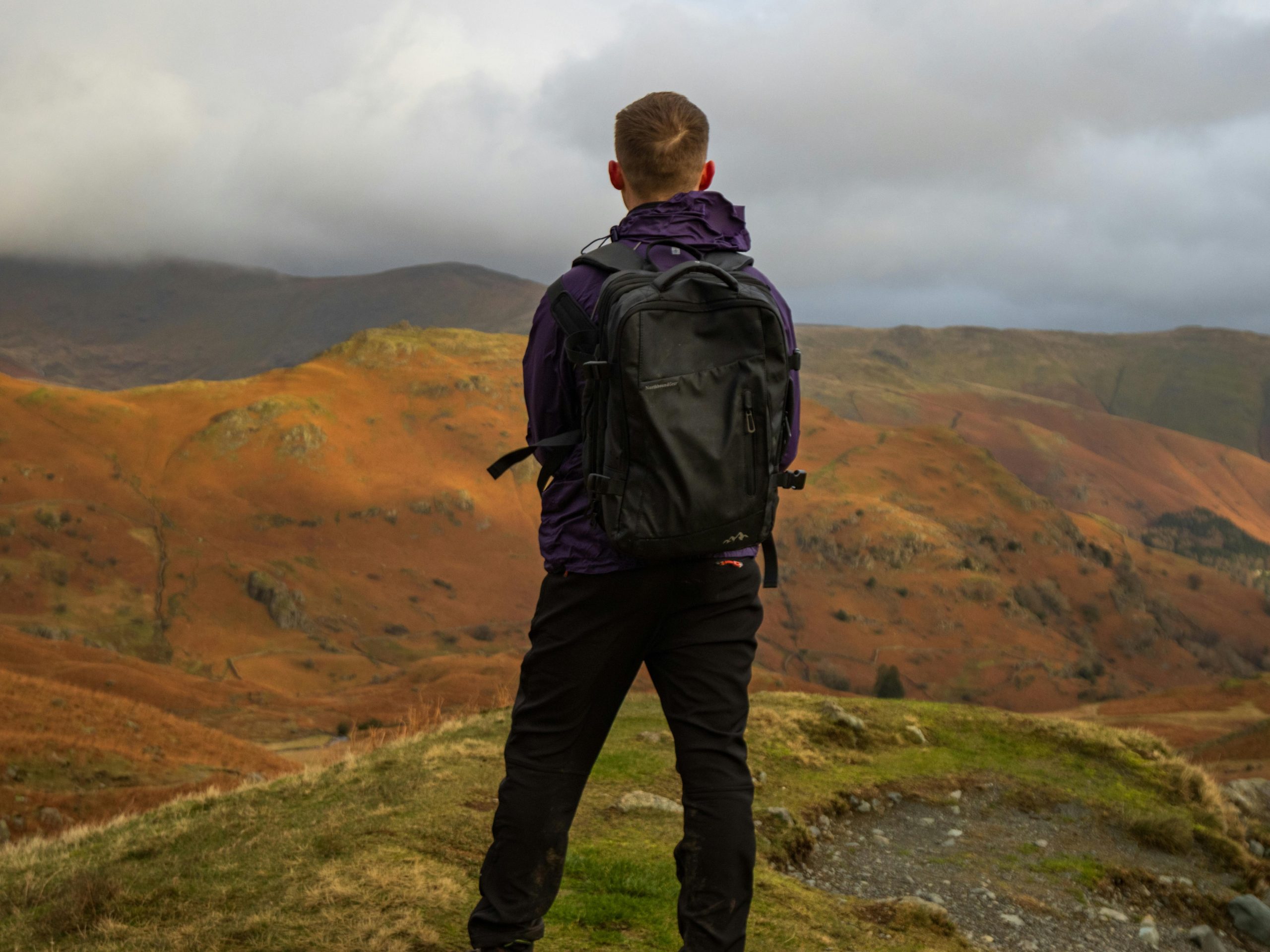 free-photo-of-man-with-backpack-hiking-on-hill